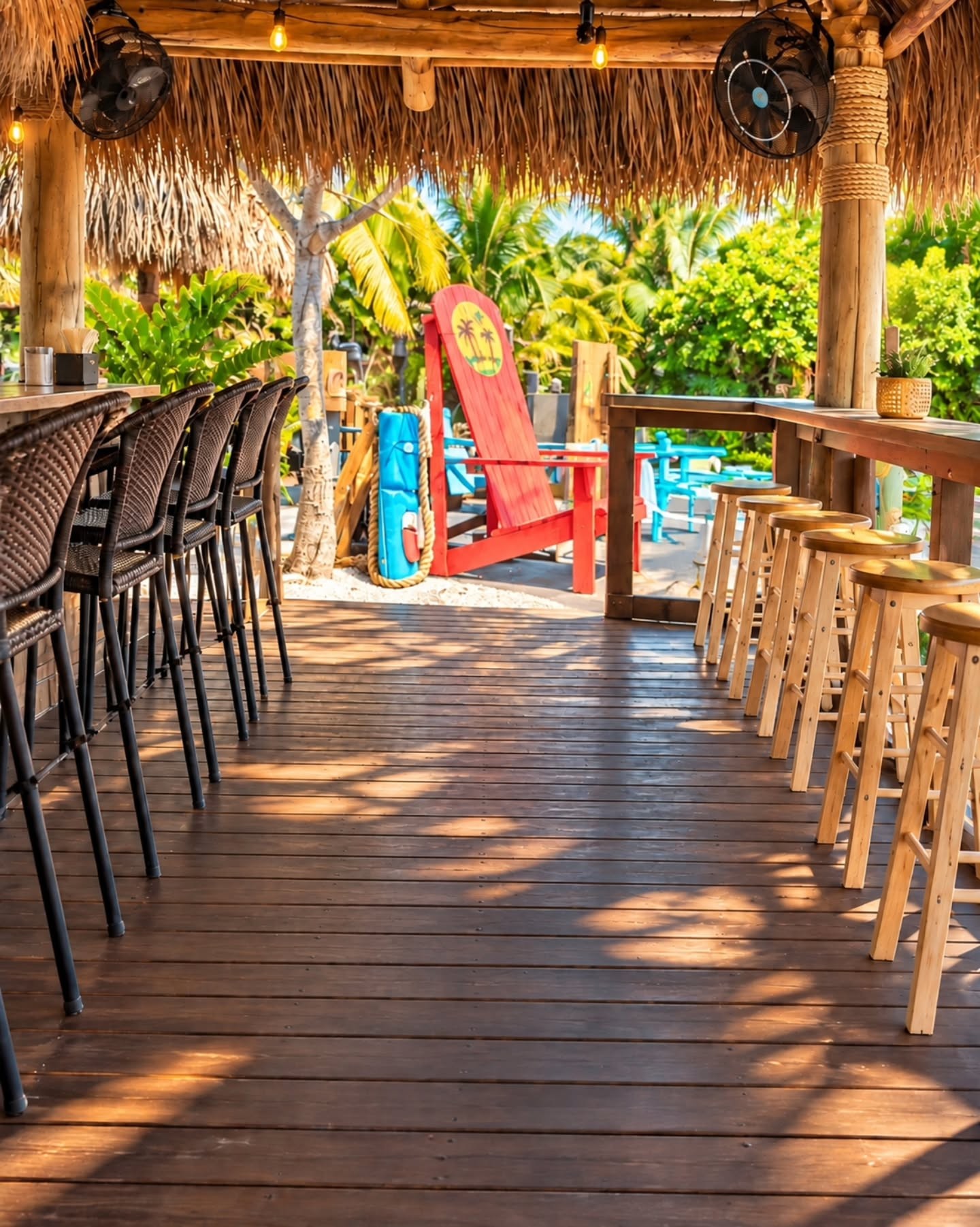 The new wooden deck with bar stools, a red Adirondack chair and tropical plants