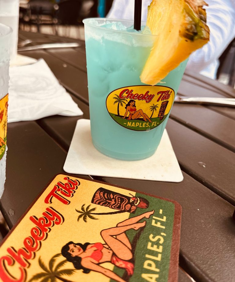 A blue tropical cocktail with a pineapple wedge on a Cheeky Tiki coaster
