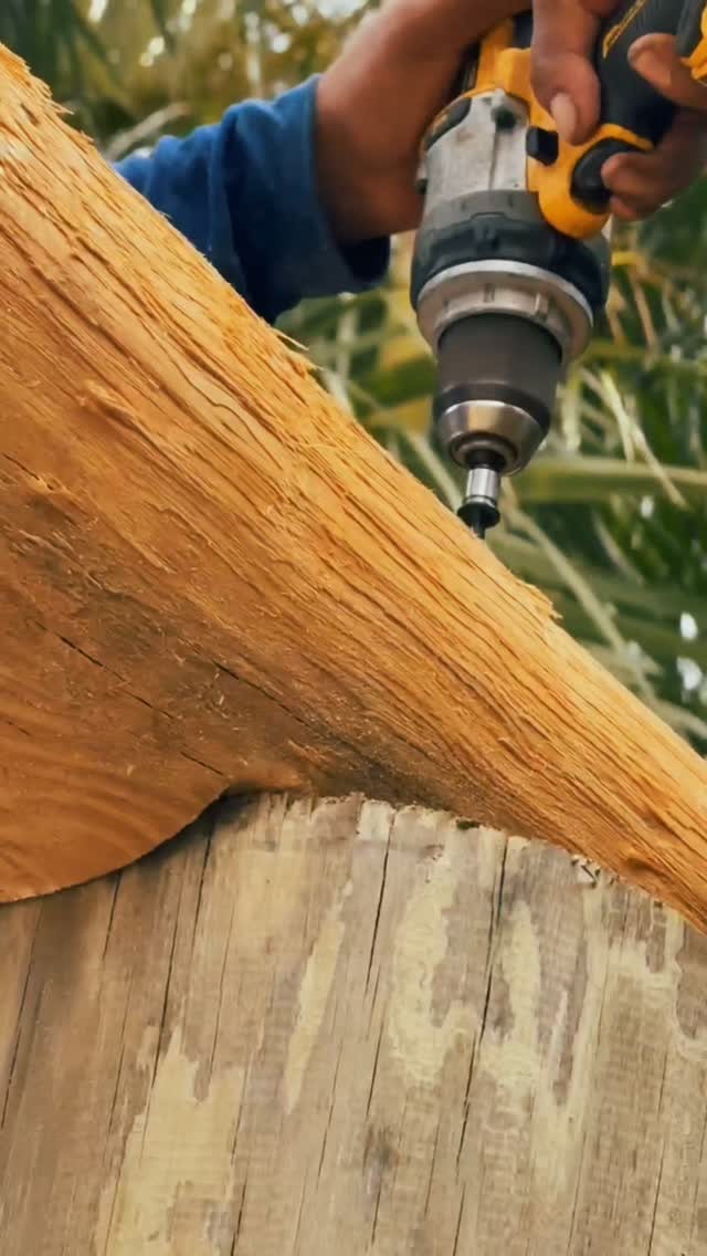 A craftsman drilling into a cypress beam during the tiki hut build